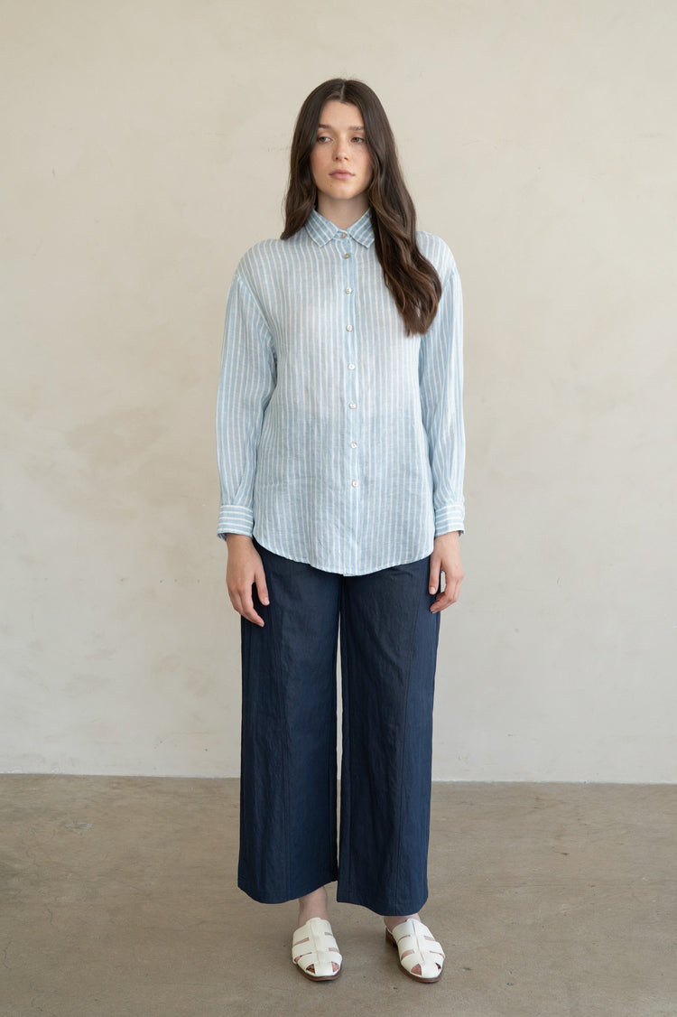 Woman wearing the Eliana Striped Linen Essential Shirt in blue and white with navy wide-leg pants.