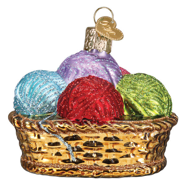 Glass Christmas ornament of a golden basket filled with glittery blue, purple, red, and green yarn.