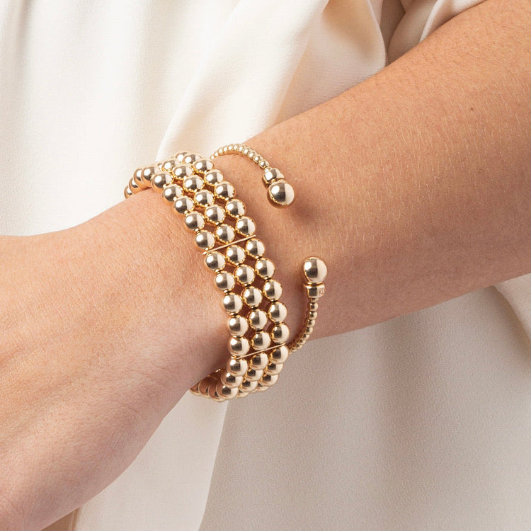 A person wearing a Classic Gold 3MM Bead Cuff made of three rows of 14kt gold-filled beads.