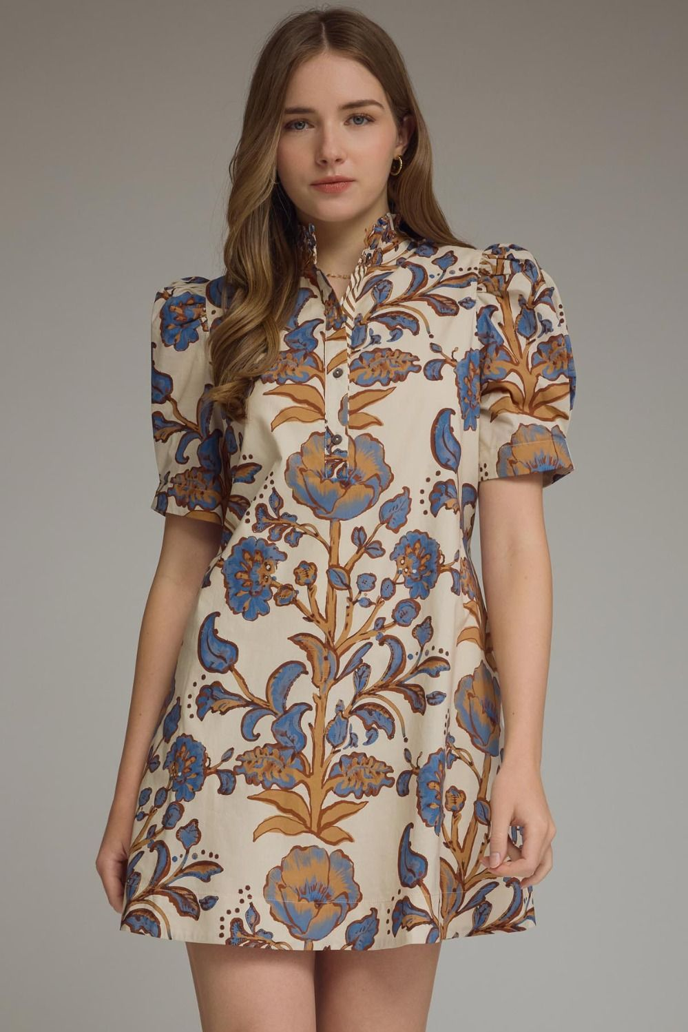 Woman wearing a Lucy floral print mini dress with short puff sleeves and a ruffled high neck.