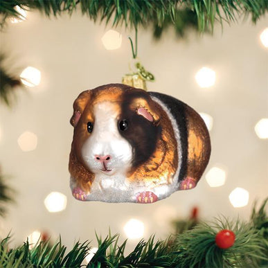 Glass guinea pig Christmas ornament with brown, white, and black fur patterns on a tree.