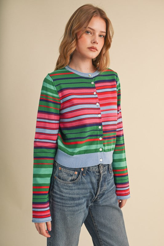Woman wearing a Vivi multi-color striped sweater cardigan with blue jeans.
