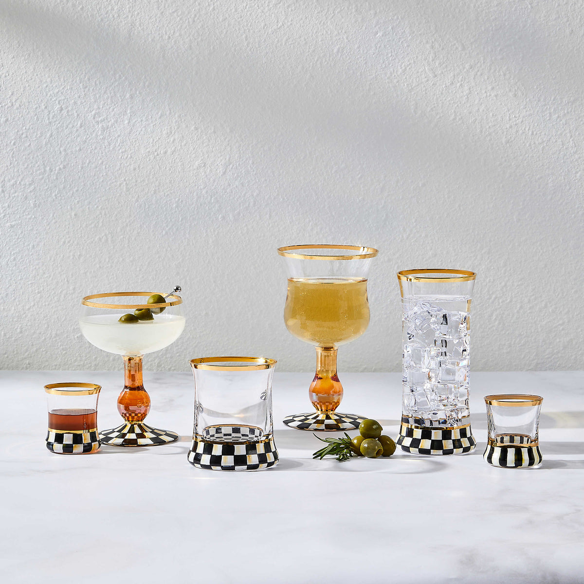 Courtly Check Coupe Glass and assorted glassware with hand-painted black and white checkered bases.