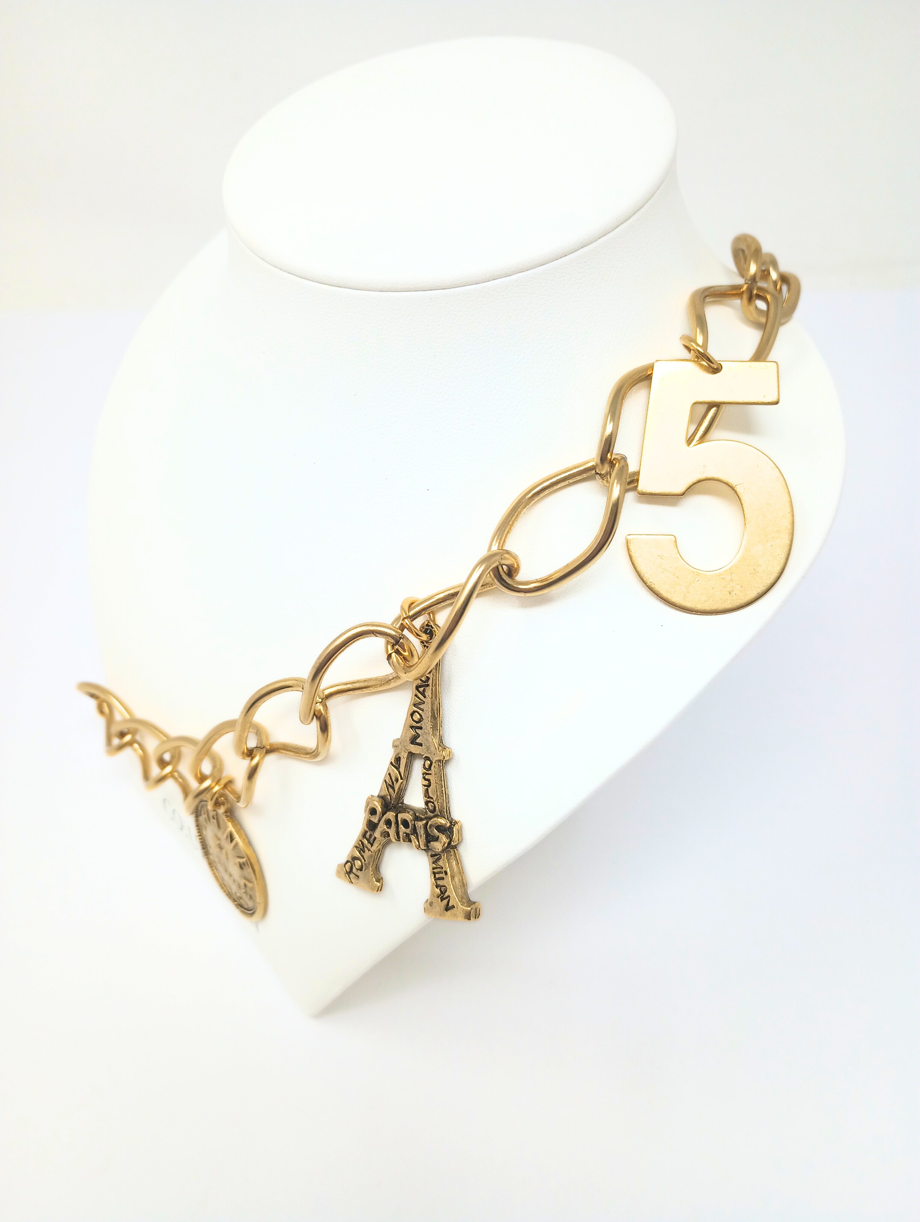 Gold link necklace featuring five charms: Paris heart, Eiffel Tower, number five, and two Chanel-style coins.