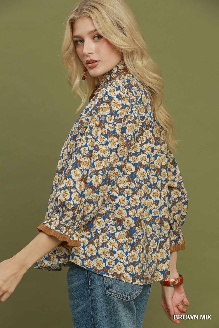 Woman wearing a Kate Mix floral print blouse with a mandarin collar and ruffled cuffs.