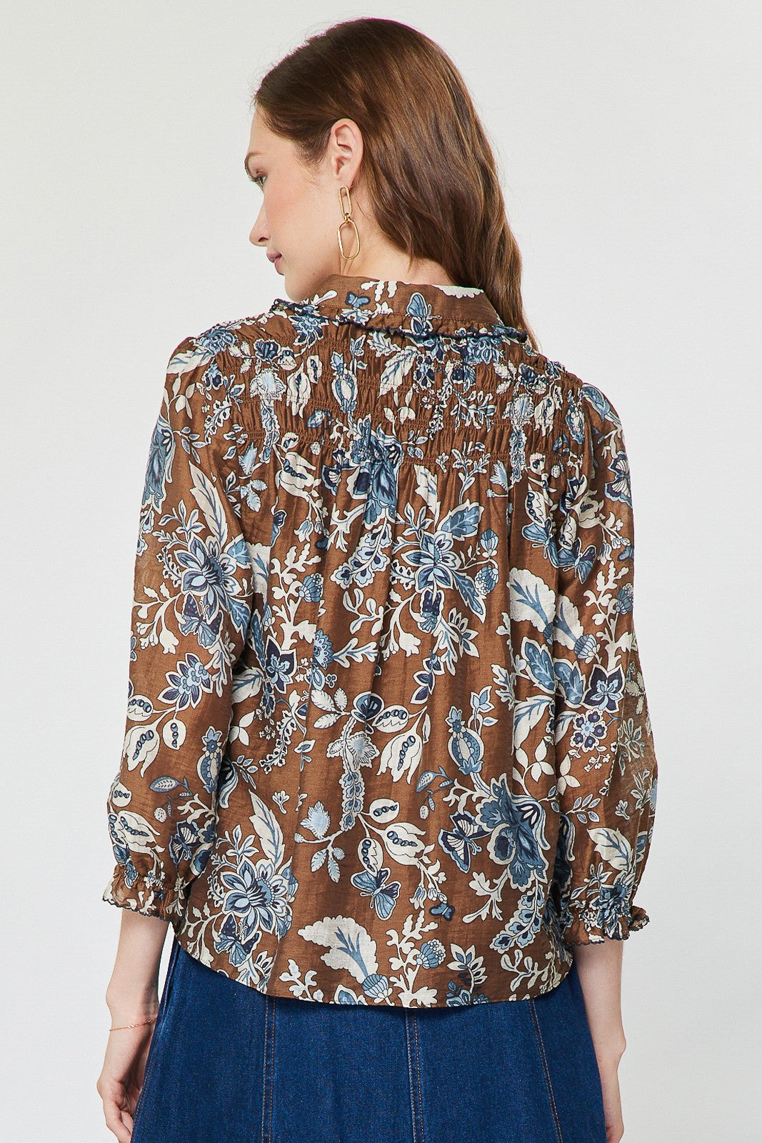 Floral paisley print sheer blouse with shirt collar, ruffled detail, half placket buttons, and smocked back.