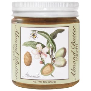 A glass jar of smooth almond butter with a label featuring a botanical almond branch illustration.