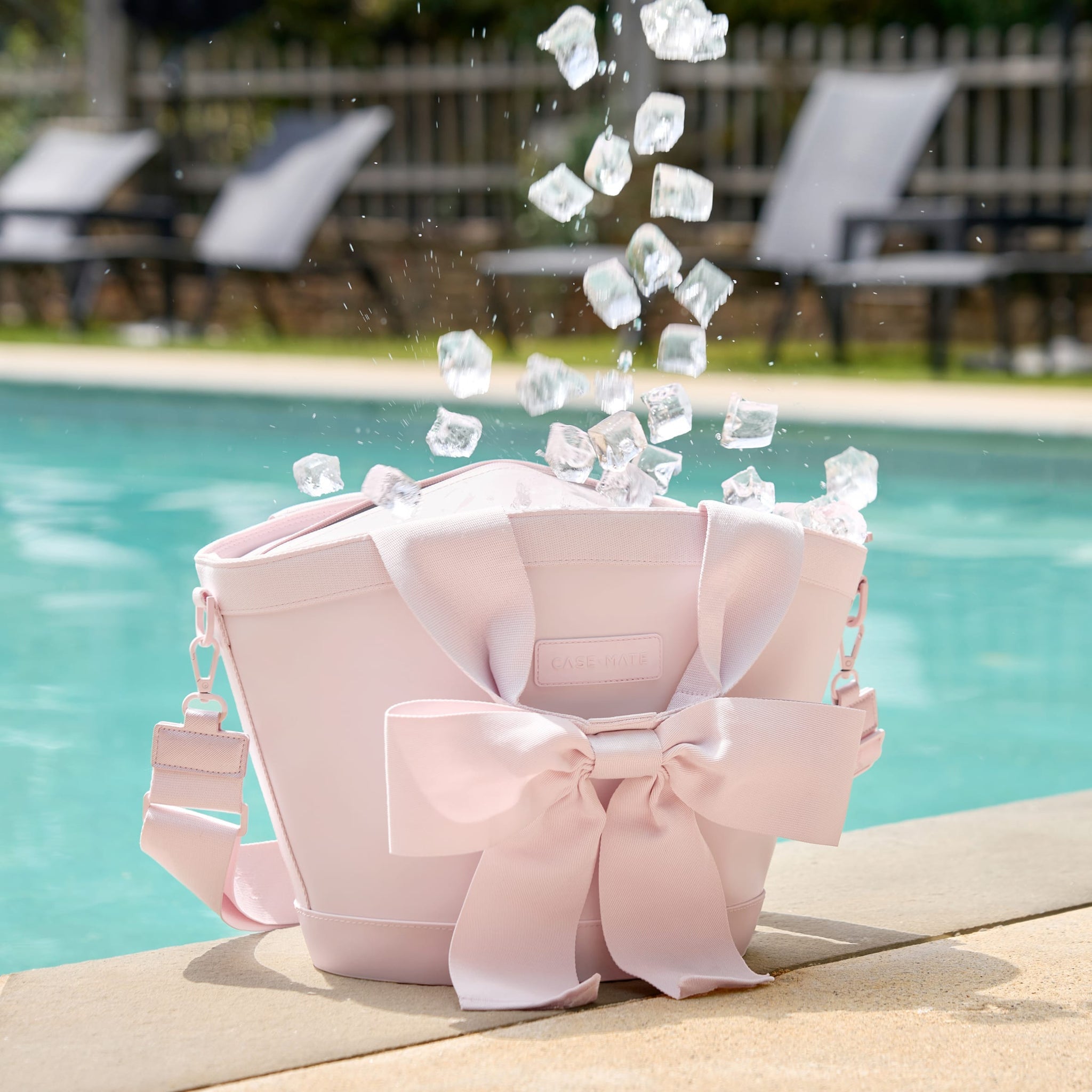 7L Jelly Cooler Tote in Ballet Pink with a large bow, sitting by a pool with ice falling into it.