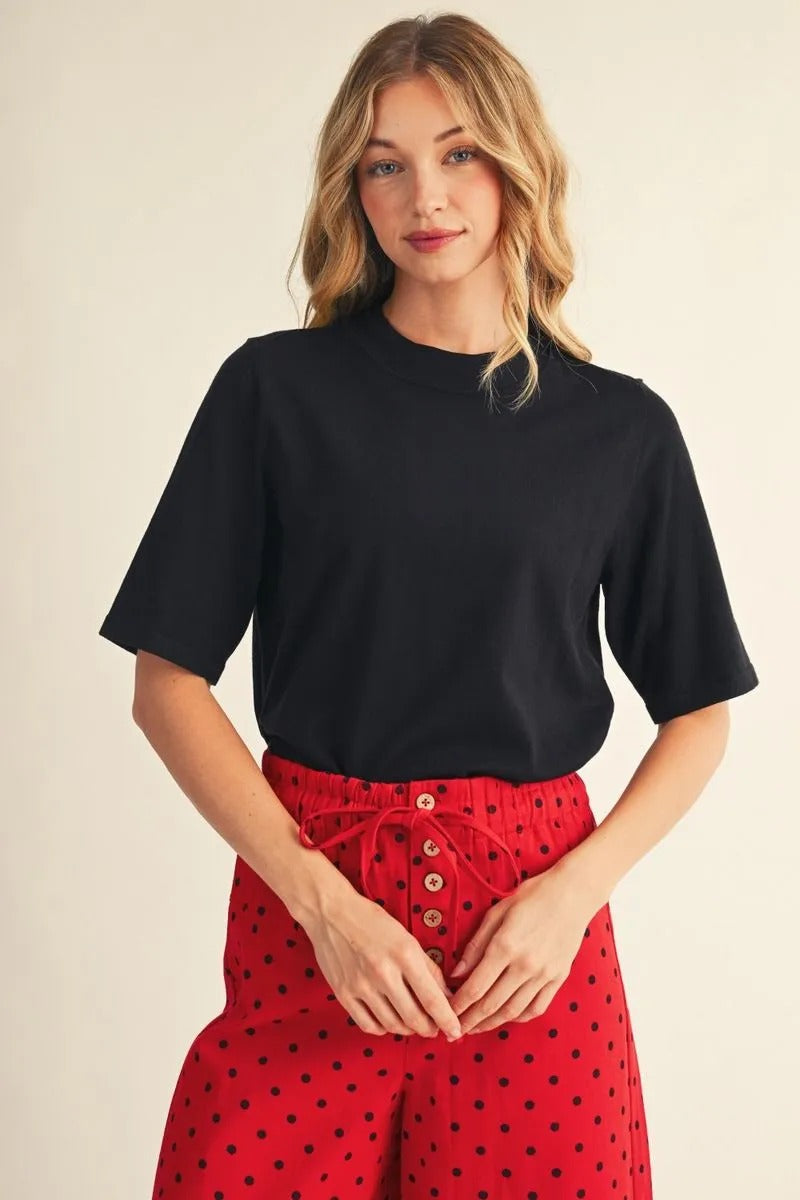 Woman wearing the Abigail black half-sleeve round neck sweater top with red polka dot pants.