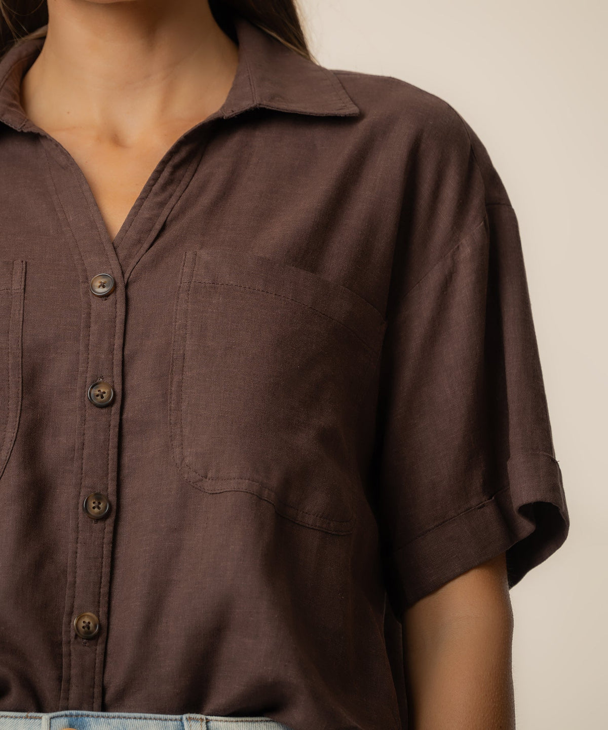 Close-up of a brown Brianna Linen Boxy Shirt with short sleeves, front pockets, and buttons.