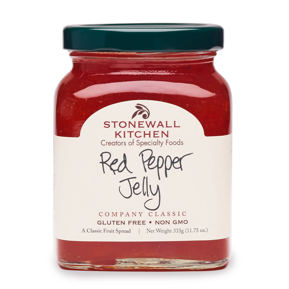 Front view of a clear glass jar containing red pepper jelly with visible fruit pieces.