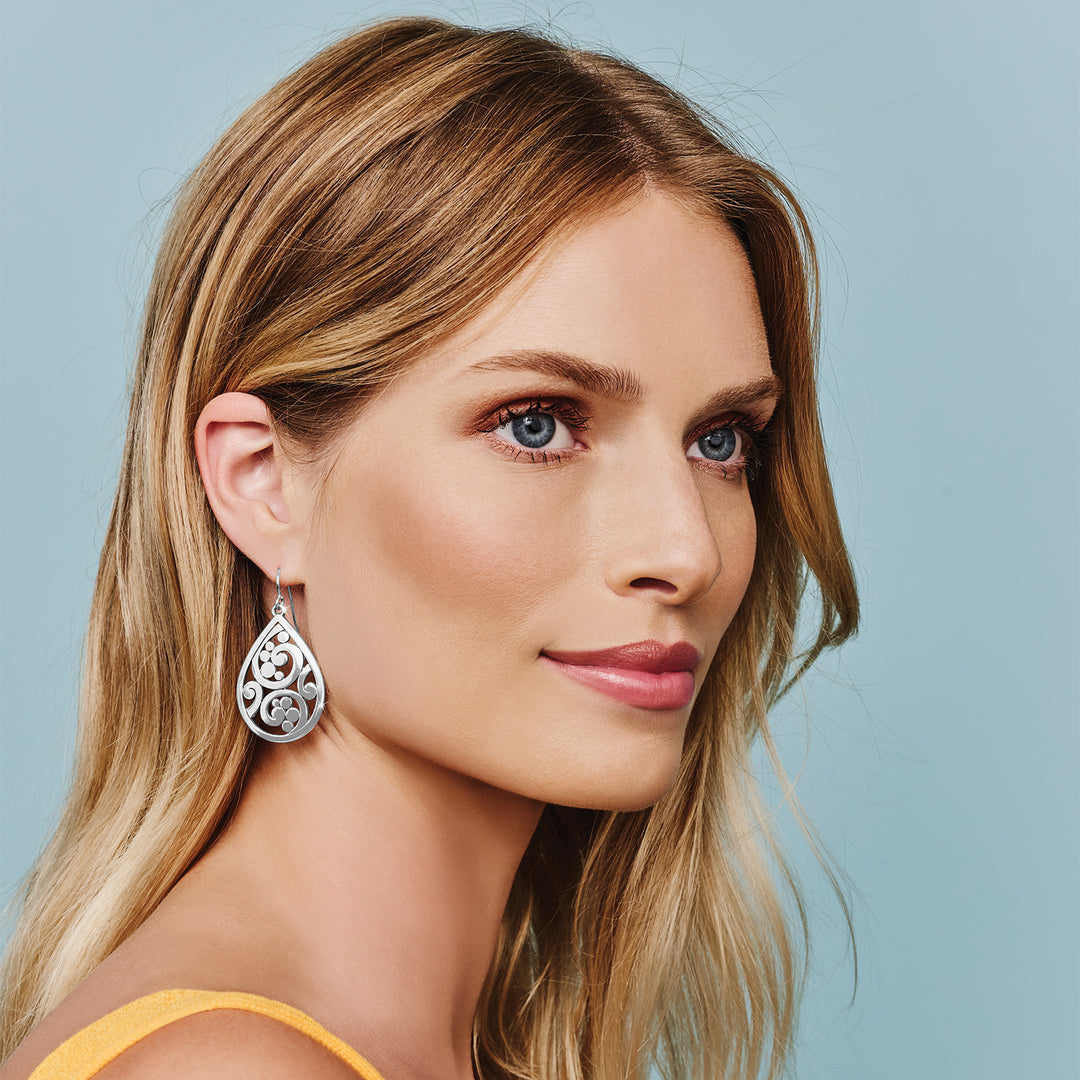 A woman wearing silver Contempo Teardrop French Wire Earrings with intricate scrollwork designs.