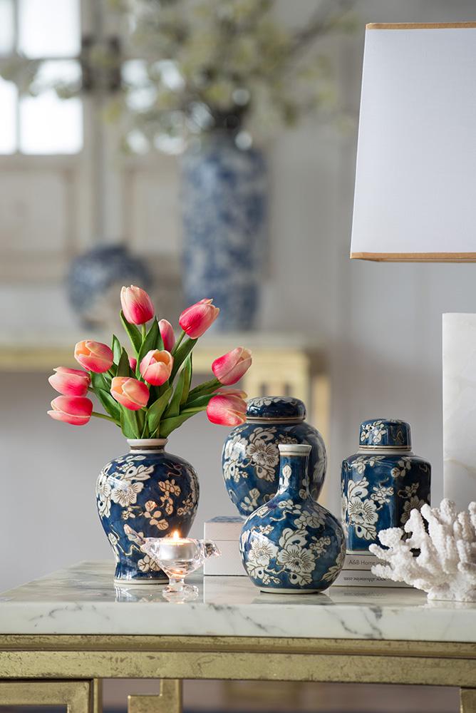 Ceramic vase with blue background, white floral print, gold accents, and graceful silhouette.