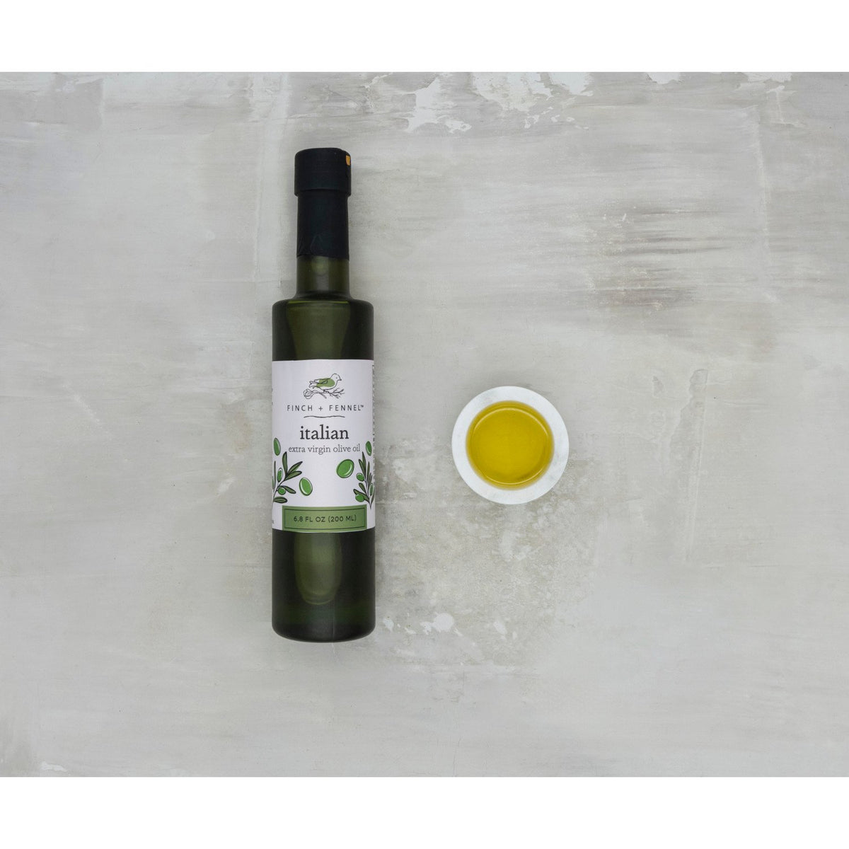 Bottle of Italian Extra Virgin Olive Oil with a clear glass body showing golden liquid and a silver cap.