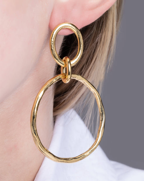 Roselene Earrings featuring two interlocking, irregular 22K gold-plated hoops on a model's ear.