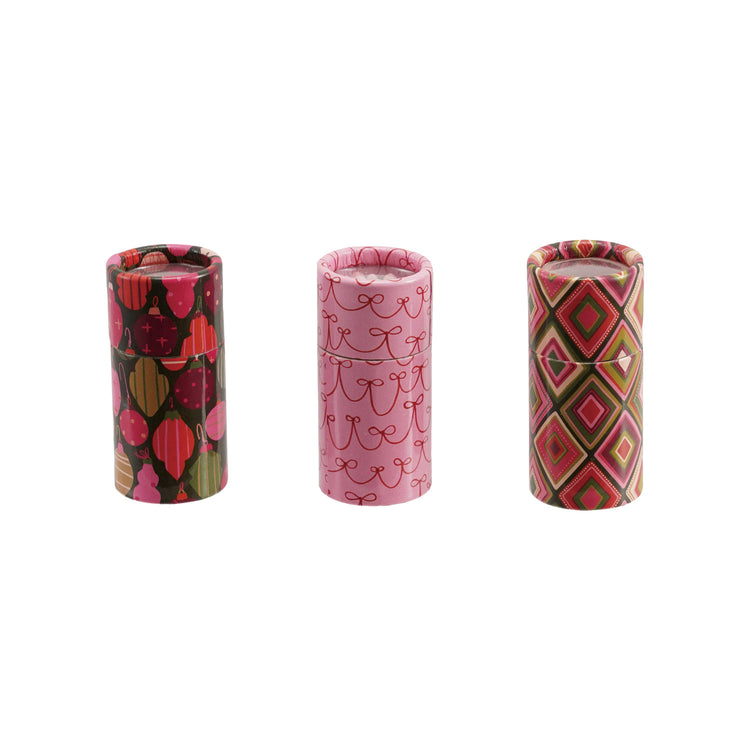 Three small tubes of safety matches with holiday patterns: ornaments, bows, and geometric diamonds.