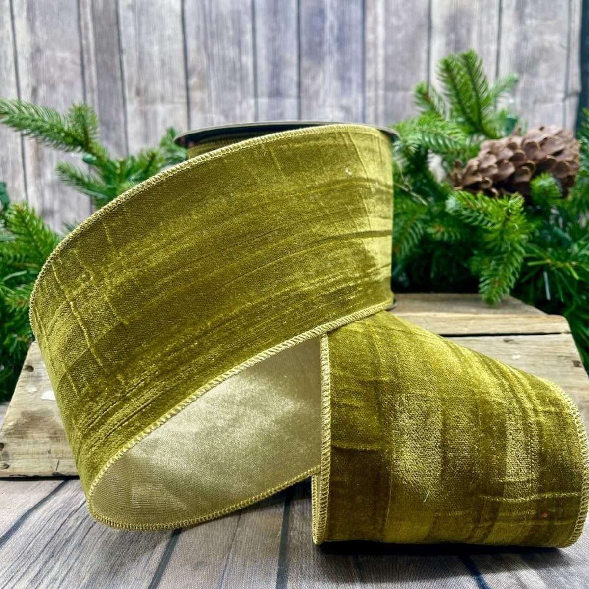 4 inch wide moss green velvet ribbon with gold backing and wired edges on a wooden surface.