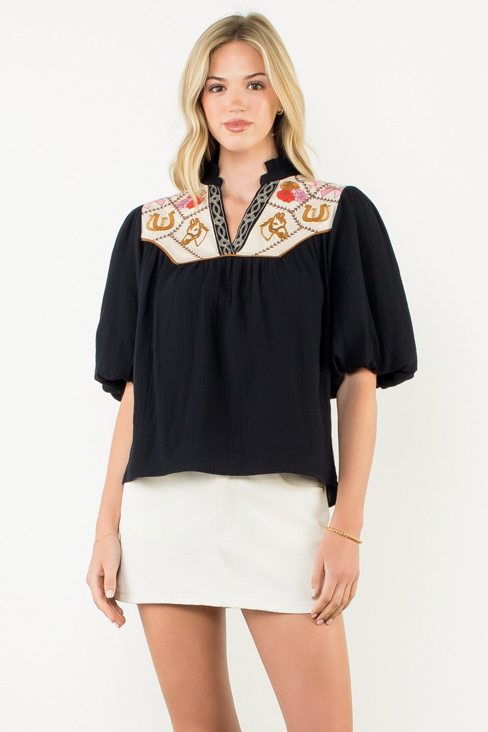 Woven cotton top with puff sleeves, embroidered neckline, and feminine silhouette in a neutral tone.