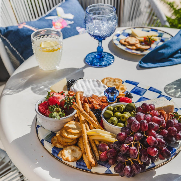 Royal Check Enamel Cheese Course platter on a table with grapes, crackers, cheese, and olives.