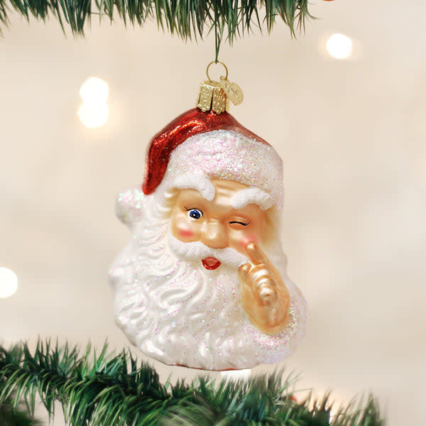 Red ceramic Santa ornament with white beard holding a finger to his nose in whimsical pose
