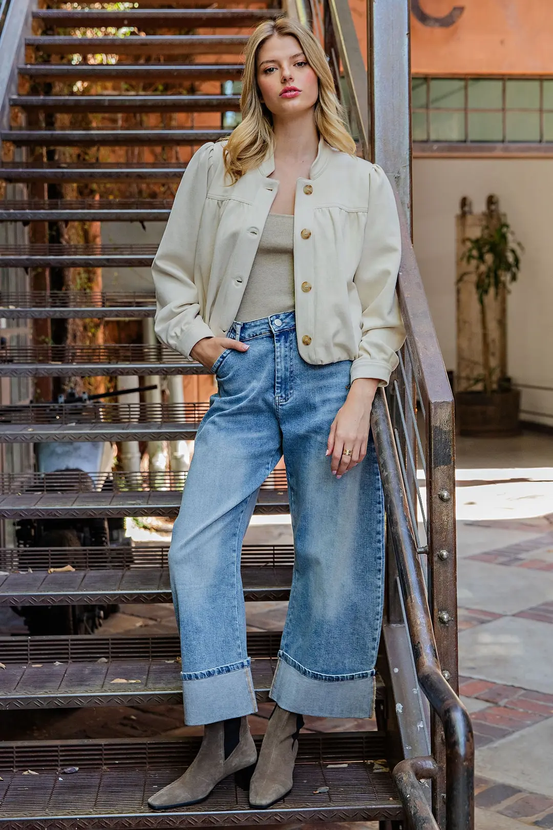 Woman wearing a cream Bette Suede Blouson Hem Button Up Jacket with wide-leg cuffed jeans.