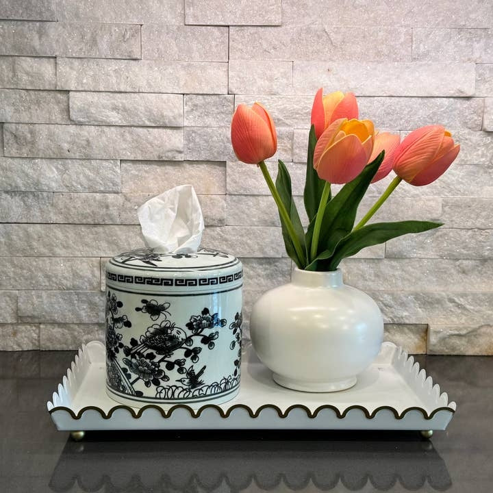 Cylindrical ceramic tissue vessel with black and white floral design on a tray next to a flower vase