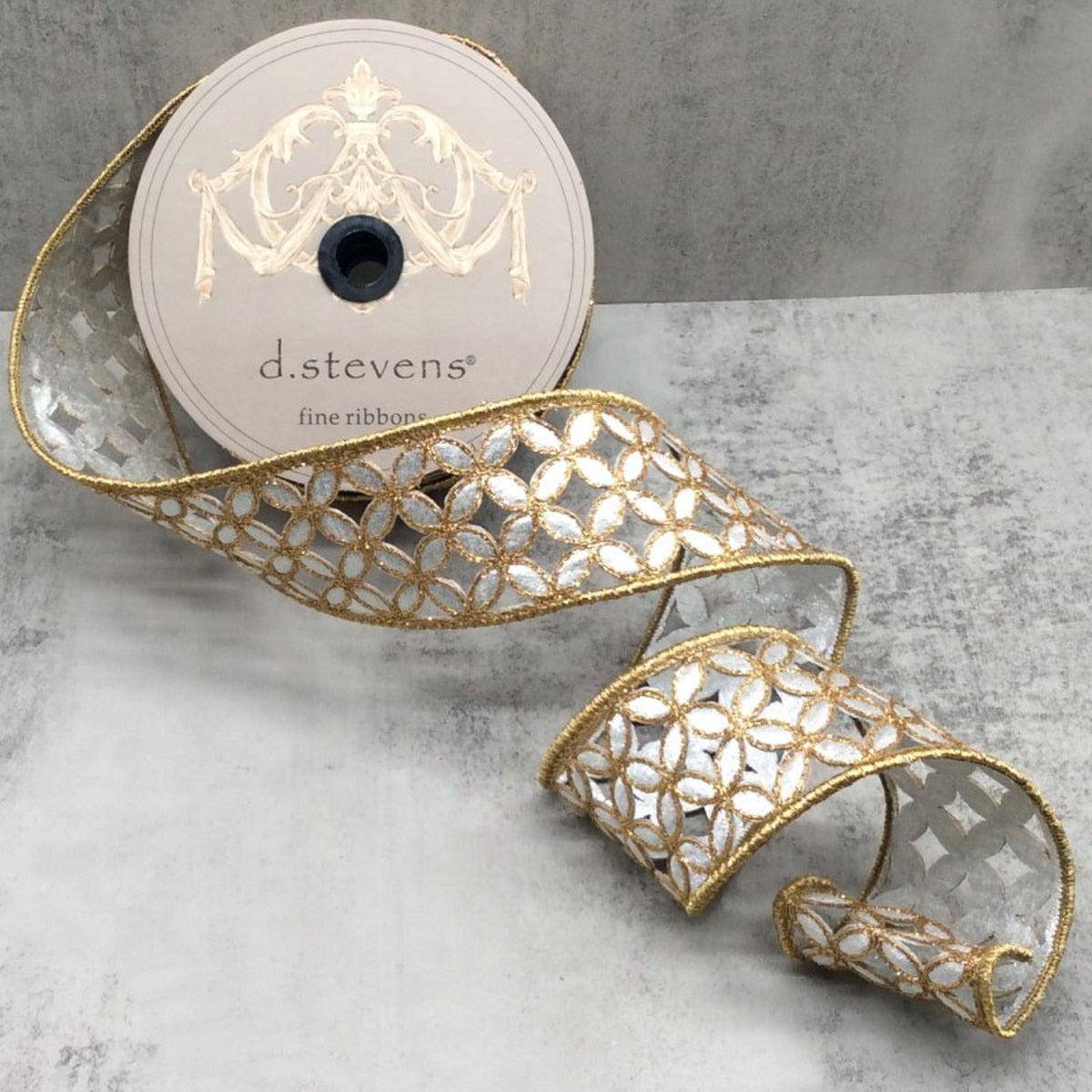 2.5 inch metallic floral ribbon in silver and gold on a spool, featuring a cutout flower pattern.