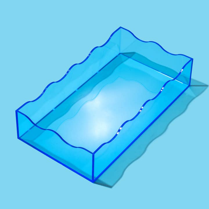 Small blue acrylic wavy rectangle tray on a light blue background.