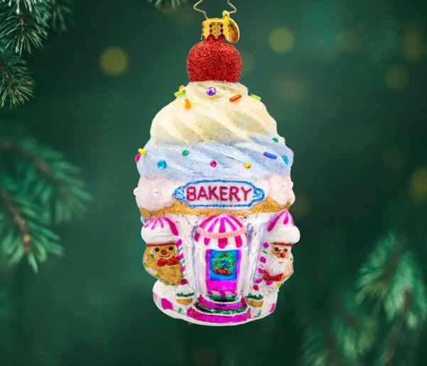 Glass bakery ornament shaped like a cupcake with a red cherry on top, decorated with sprinkles and a "Bakery" sign.