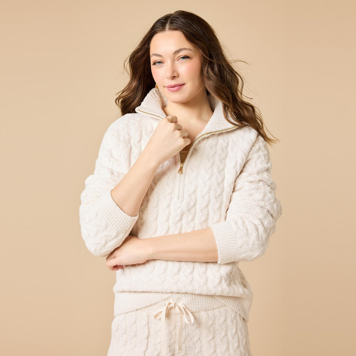 Woman wearing a cream cable knit marshmallow 1/2 zip pullover and matching tapered pants.