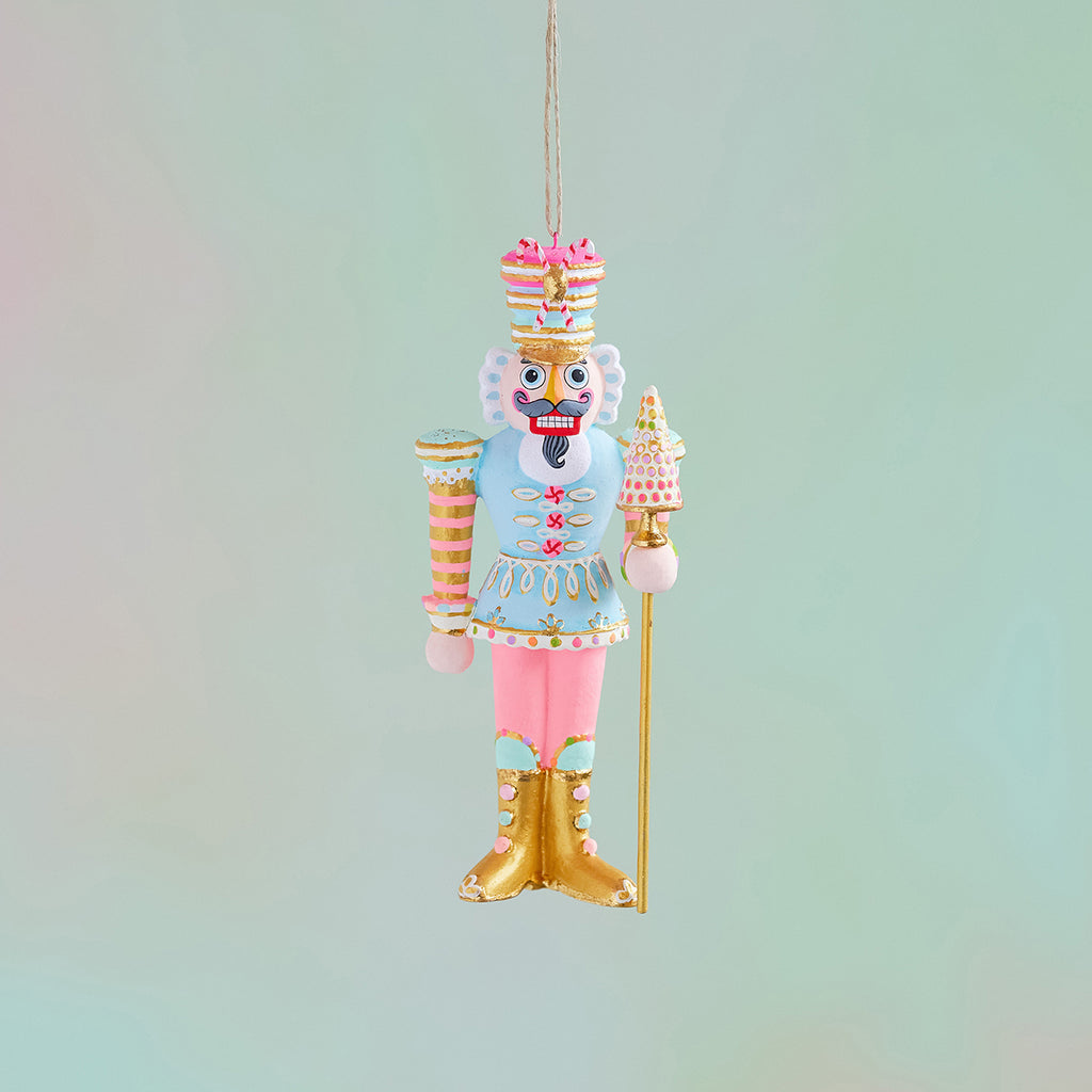 Major Macaron nutcracker ornament, hand-painted in pastel blue and pink with gold leaf accents.