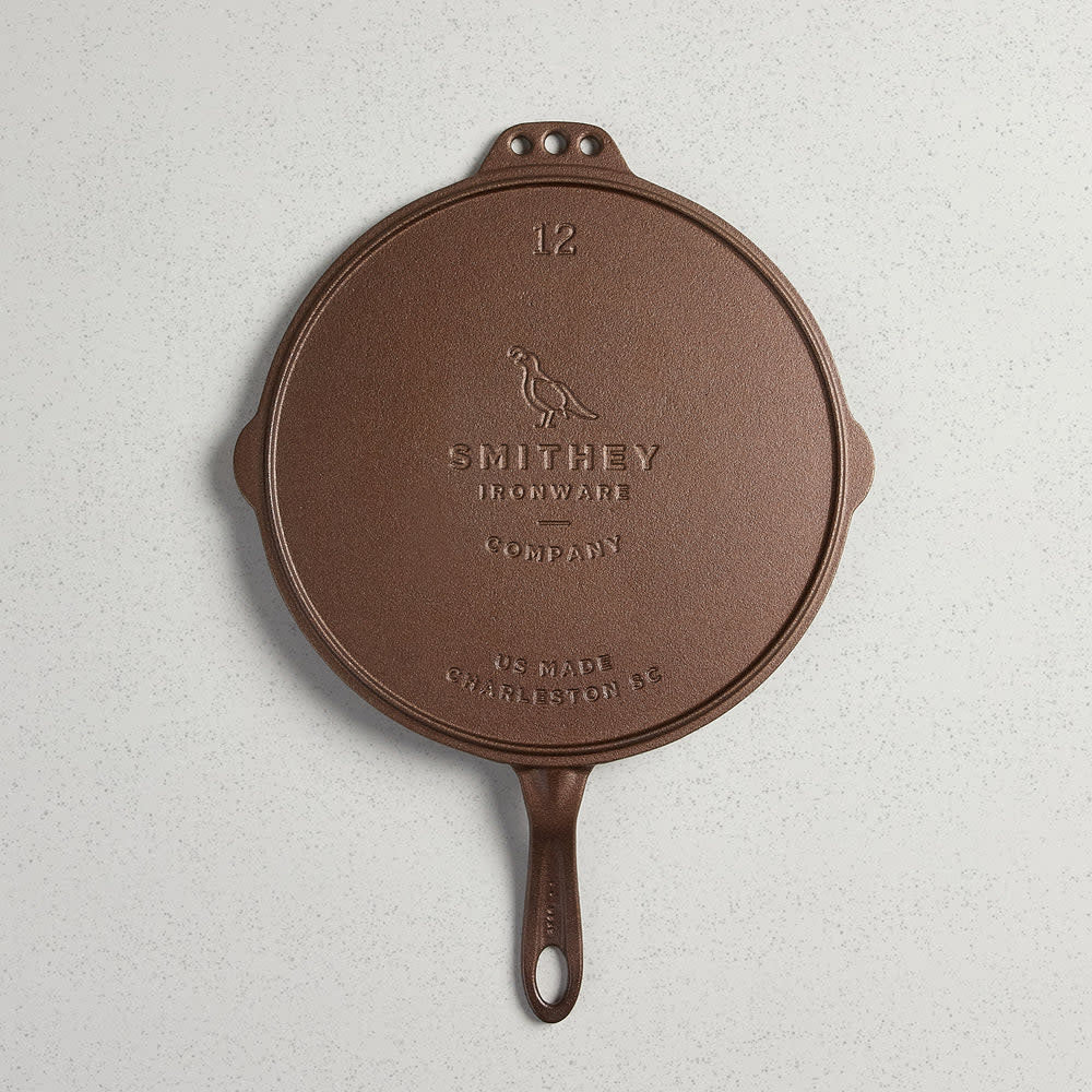 Polished stainless steel No. 12 flat top griddle with pour spout and two hanging holes.
