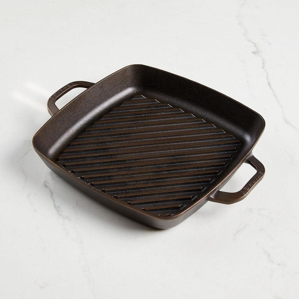 Square stainless steel grill pan with diagonal raised ridges and dual ergonomic handles.
