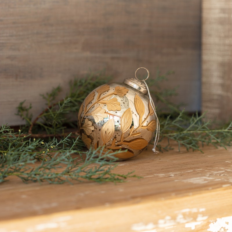 Round 4-inch antique mercury glass ornament with gold etched botanical leaf patterns.