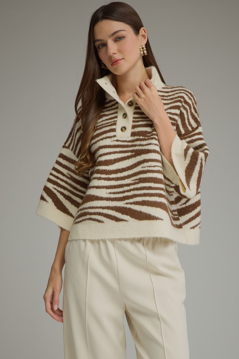 Woman wearing a Chanice abstract animal print 3/4 sleeve knit top with a stand neck and buttons.