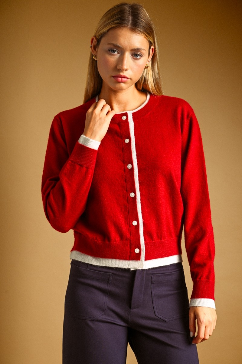 Woman wearing a red Julia cropped cardigan with white contrast trim and button-front closure.