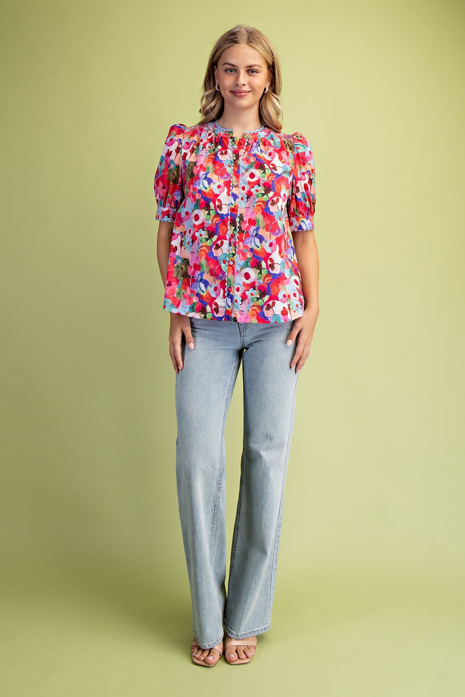 Woman wearing a Sophia Bold Floral Button Down Blouse with light wash jeans.