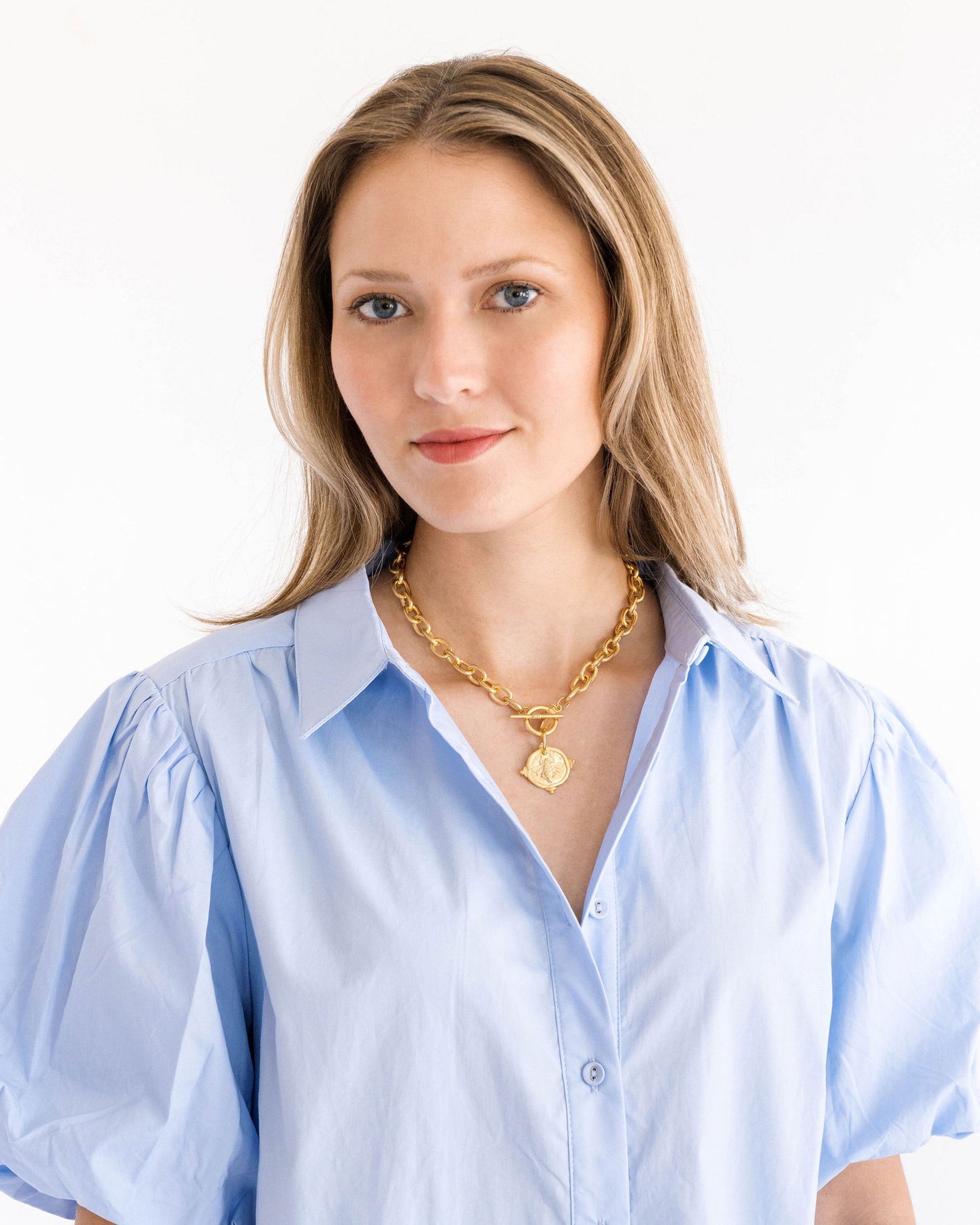 Woman wearing a gold Bee Intaglio Toggle Necklace with a light blue button-down shirt.