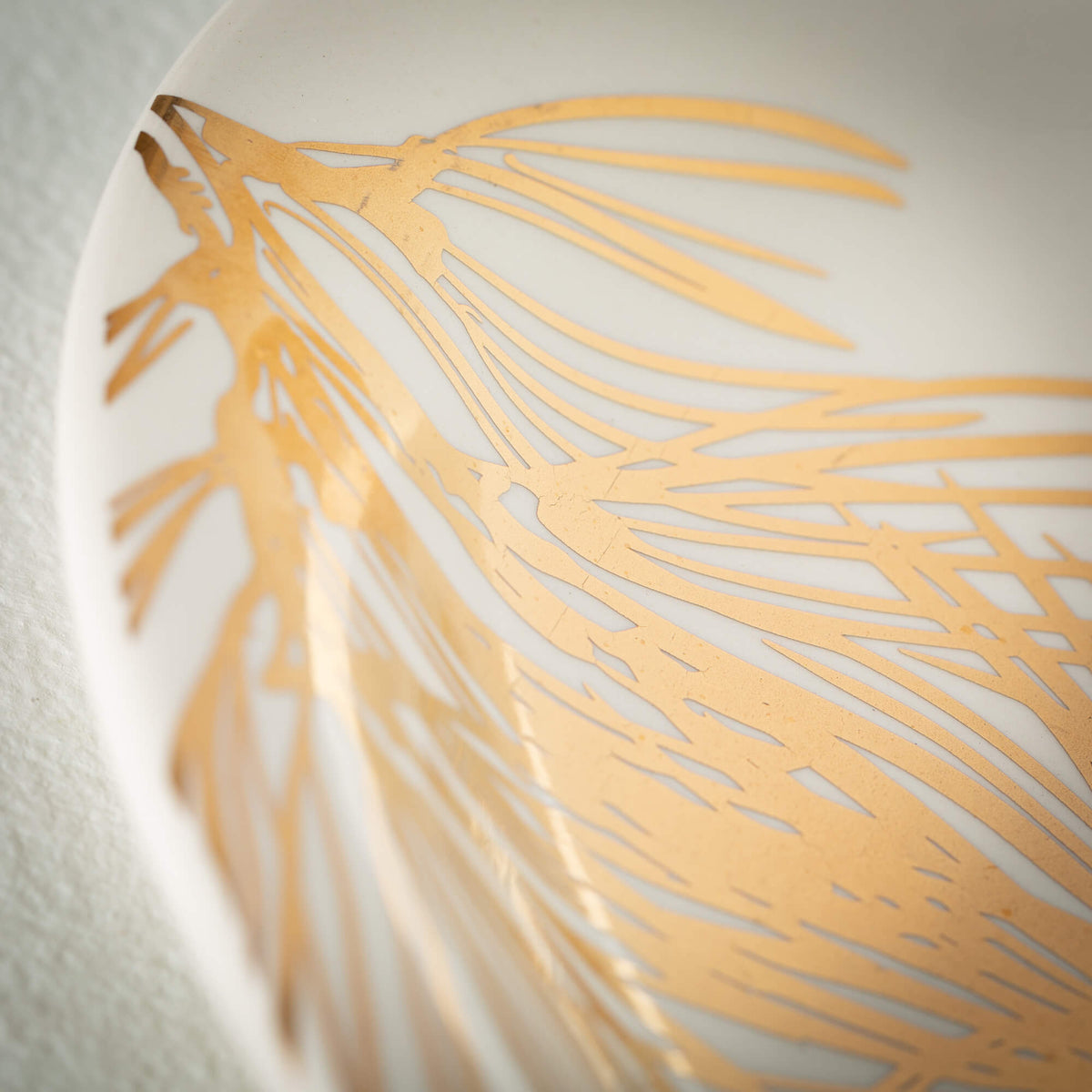 Close-up of a white ceramic Pine Platter featuring a metallic gold pine needle design.