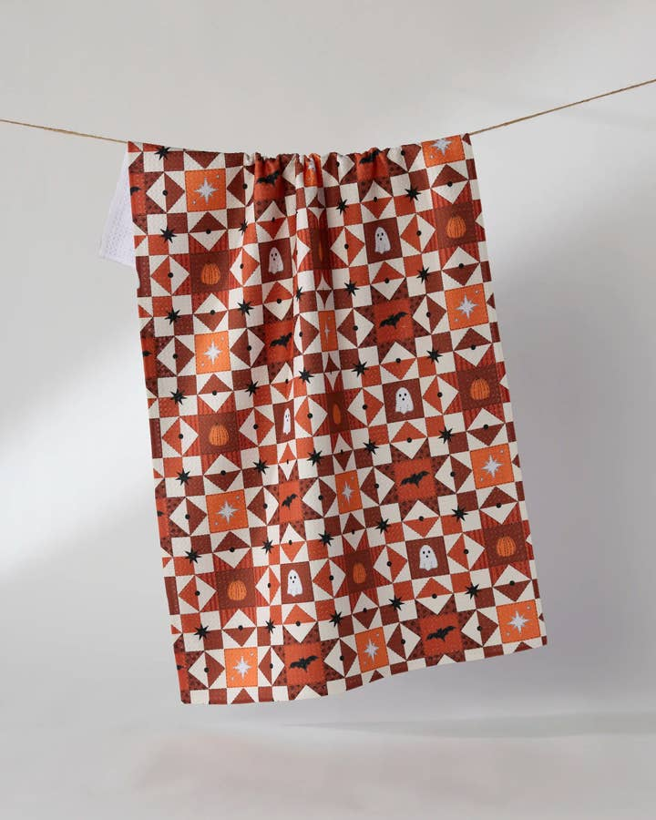 Halloween tea towel with orange and brown quilt pattern featuring ghosts, pumpkins, and bats.