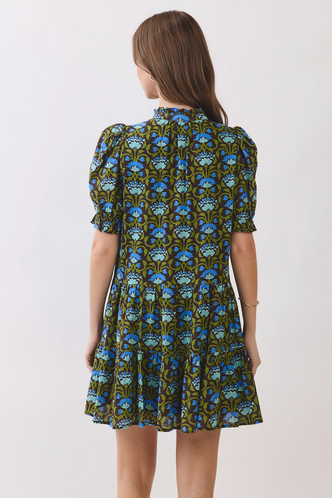 Back view of a tiered floral print mini dress with short puff sleeves and a high ruffle neckline.