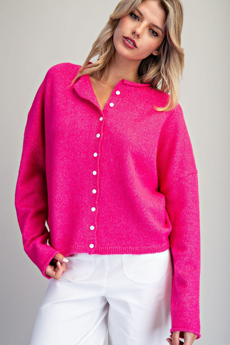Woman wearing the Eva Knit Cardigan in bright pink with white buttons and white pants.