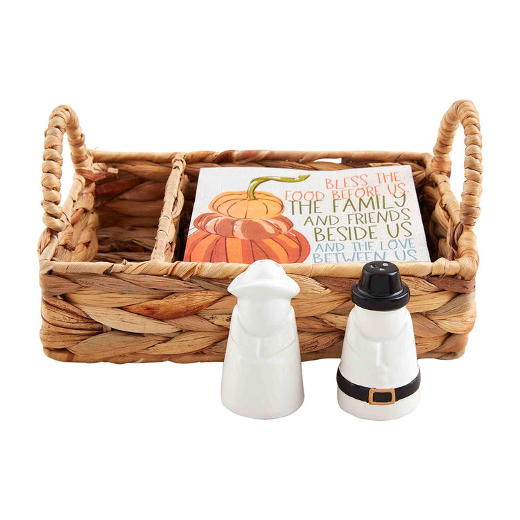 Woven basket set with pilgrim salt and pepper shakers and pumpkin-themed napkins.