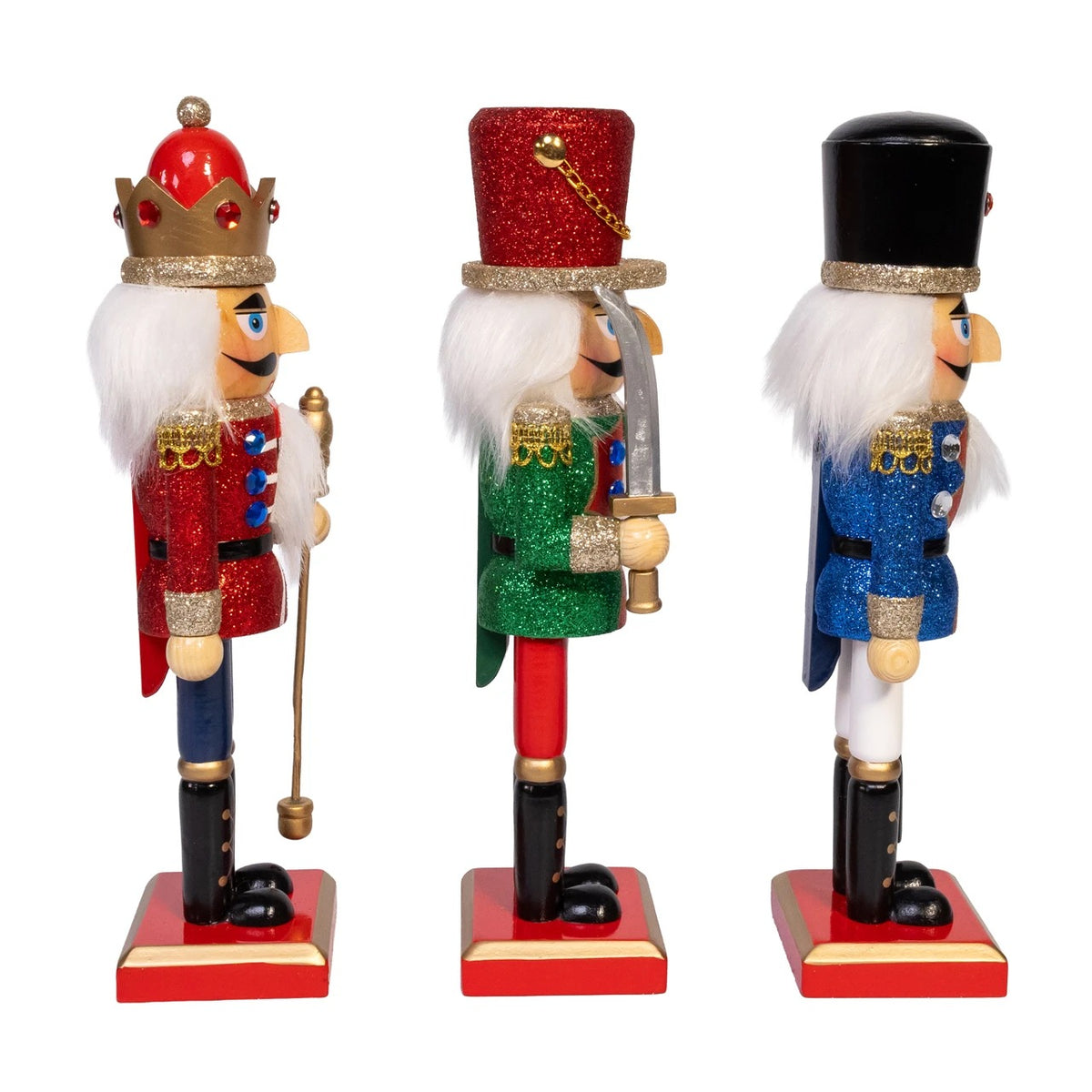 Three 10-inch wooden nutcrackers in red, green, and blue glittery outfits standing on red bases.