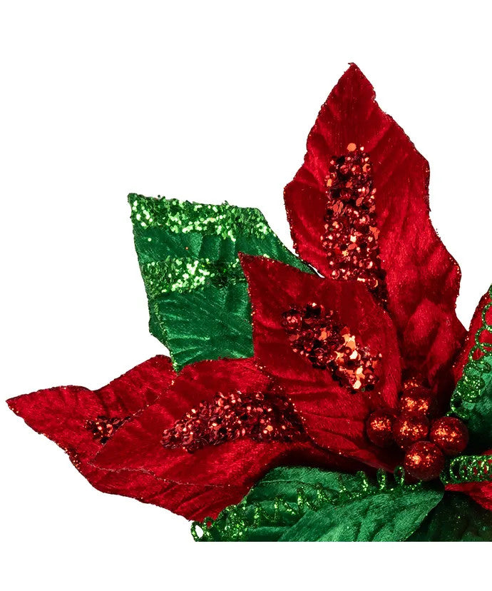 Close-up of a red and green velvet poinsettia pick with glitter accents on the petals and leaves.