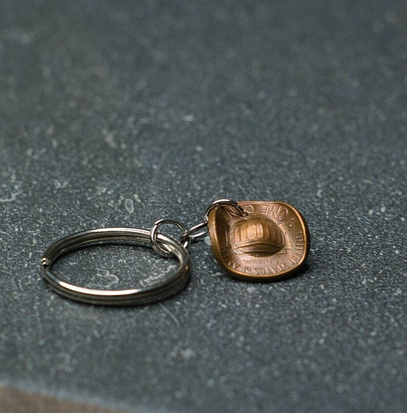 A keychain featuring a copper penny shaped into a miniature cowboy hat on a silver metal ring.