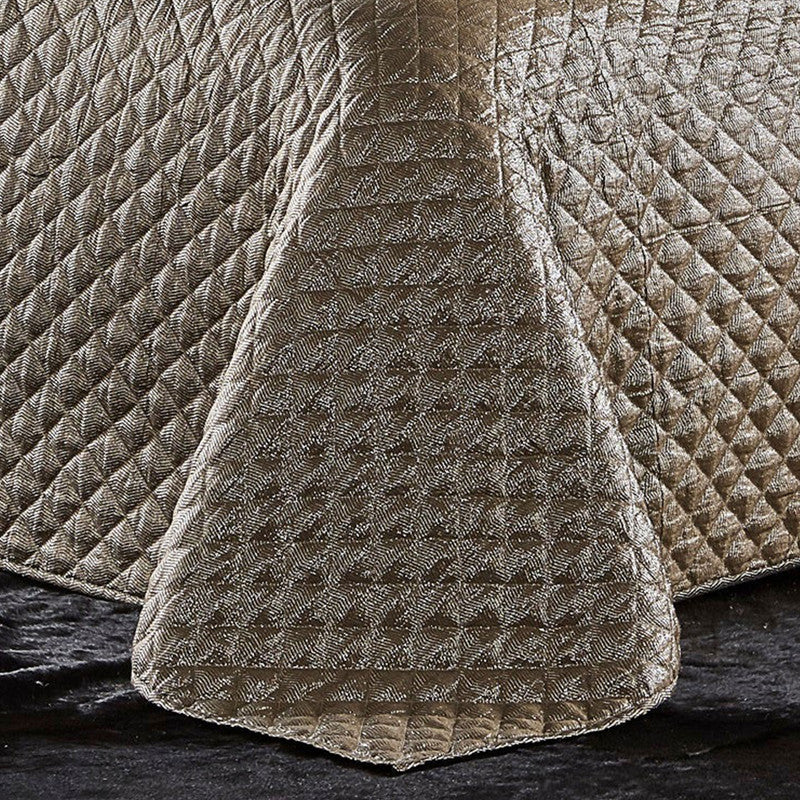 Close-up of the Aura Gold Quilt showing the metallic gold fabric and diamond quilted pattern.