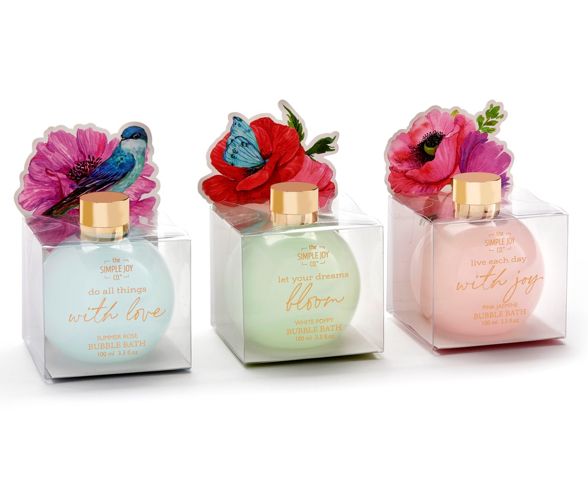 Three bubble bath bottles in clear packaging with floral and bird/butterfly toppers. Left: blue bottle, "do all things with love". Middle: green bottle, "let your dreams bloom". Right: pink bottle, "live each day with joy".