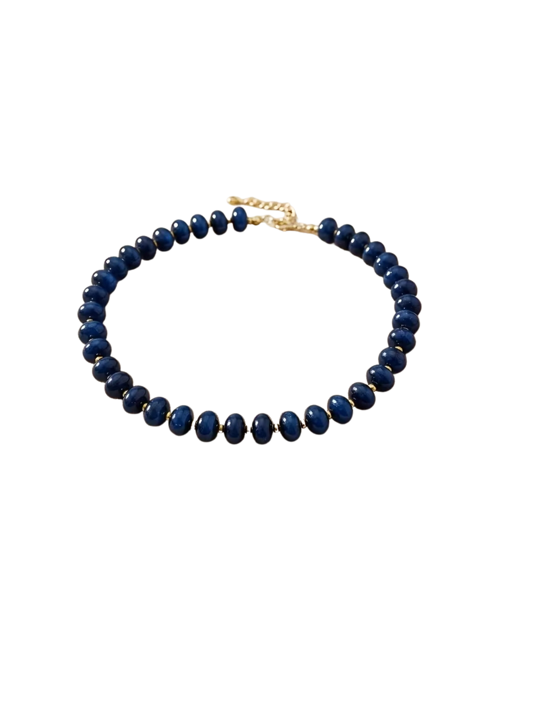 Boho beaded necklace with smooth navy blue beads and gold-tone spacers on a white background.