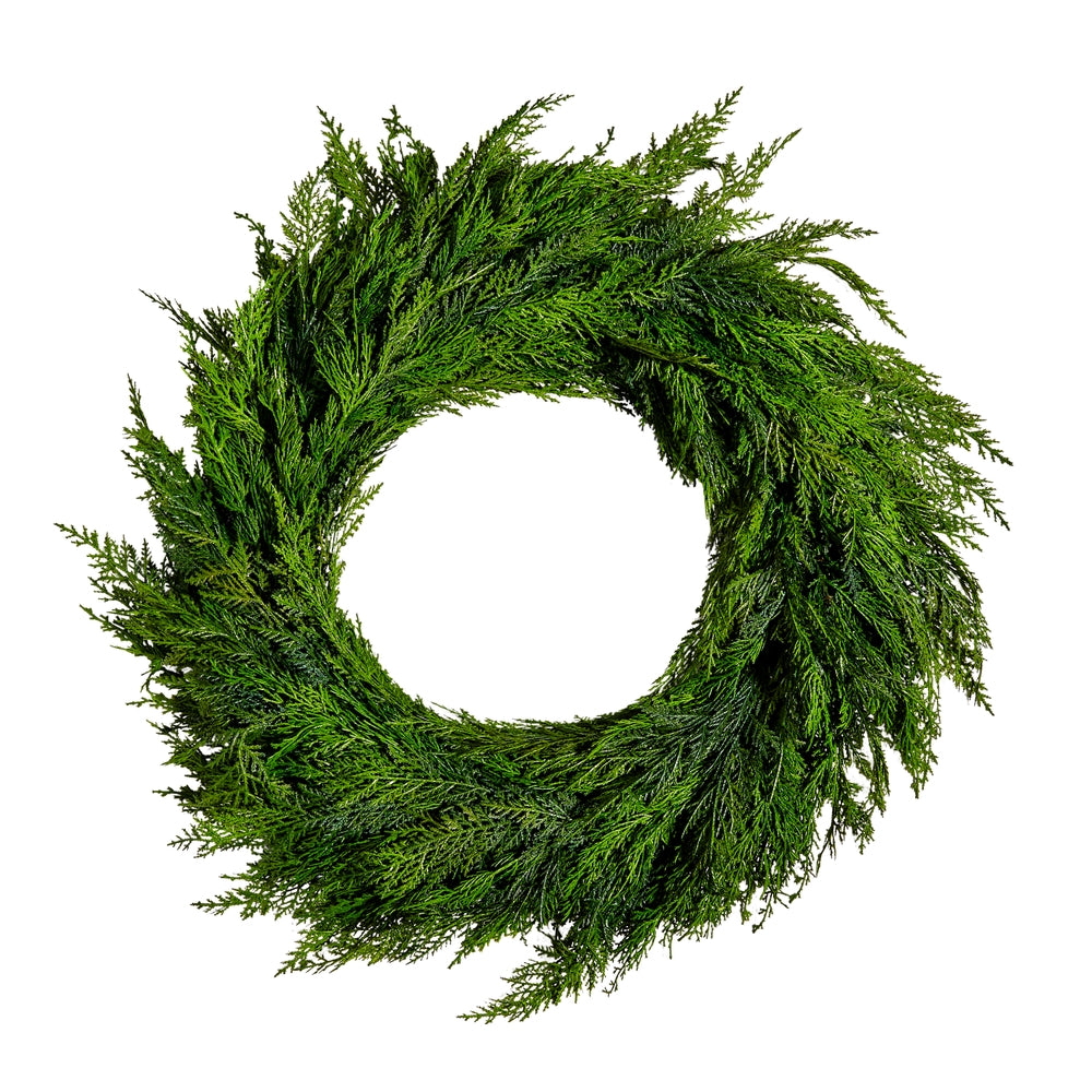 Round cedar wreath with natural green foliage on a dark brown background.
